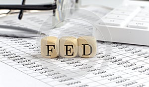 wooden cubes with the word FED on a financial background with chart, calculator, pen and glasses, business concept