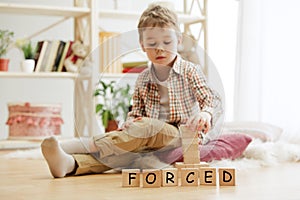 Wooden cubes with word FORCED in hands of little boy