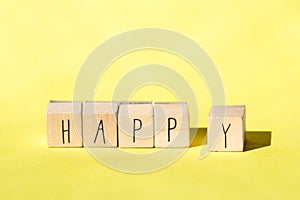 Wooden cubes with the word Happy on Bright Yellow background, Cheerful concept