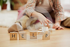 Wooden cubes with word HELP in hands of little boy