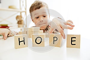 Wooden cubes with word HOPE in hands of little boy