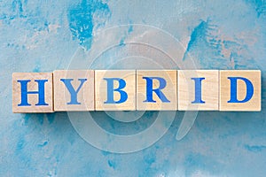 Wooden cubes with word HYBRID on blue table.