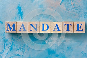 Wooden cubes with word MANDATE on blue table.