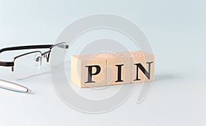 Wooden cubes with the word PIN on financial background with chart, calculator, pen and glasses, business concept