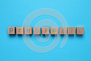 Wooden cubes with word Prebiotic on light blue background, flat lay