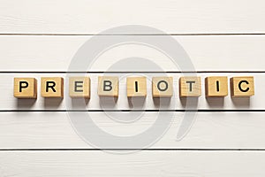 Wooden cubes with word Prebiotic on white table, flat lay