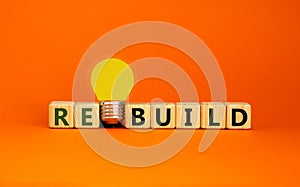 Wooden cubes with word `rebuild`. Yellow light bulb. Beautiful orange background. Business concept. Copy space