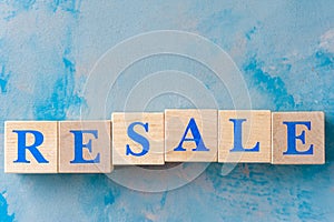 Wooden cubes with word RESALE on blue table. photo