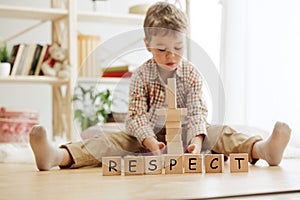 Wooden cubes with word RESPECT in hands of little boy photo