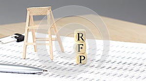 wooden cubes with the word RFP stand on a financial background, business concept