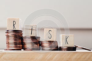 Wooden cubes with the word Risk and pile of coins, money climbing stairs. Business concept