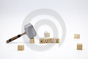 The wooden cubes with the word RULE and the weapon around against white background. The medieval hammer on a wooden cube
