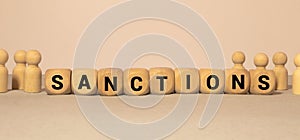 Wooden cubes with the word SANCTION stand on a wooden background between a magnifying glass and a pen