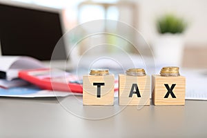 Wooden cubes with word TAX and coins