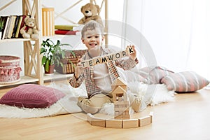 Wooden cubes with word TEAMWORK in hands of little boy