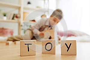 Wooden cubes with word TOY in hands of little boy