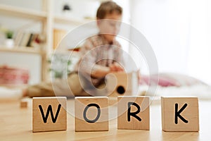Wooden cubes with word WORK in hands of little boy