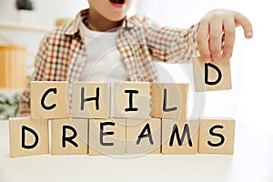 Wooden cubes with words CHILD DREAMS in hands of little boy