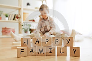 Wooden cubes with words HAPPY FAMILY in hands of little boy