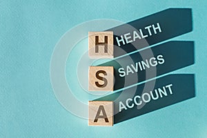 Wooden cubes with words HSA Health Savings Account with shadows. Beautiful blue background. Business and HSA concept