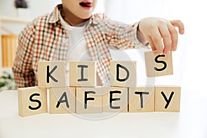 Wooden cubes with words KIDS SAFETY in hands of little boy
