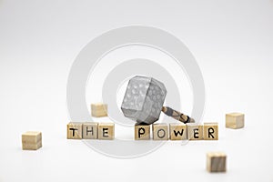 The wooden cubes with the words THE POWER and the weapon around against white background. The medieval hammer on a wooden cube