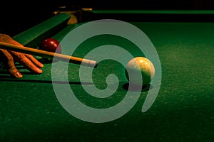 Wooden cue aiming at white billiard ball