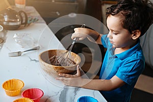 A wooden cup with a dough in the hands of a child