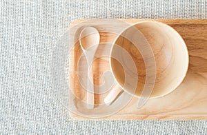 Wooden cup and spoon with saucer on grey textile