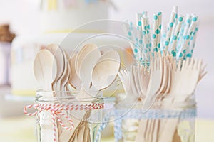 Wooden cutlery and paper straws in jam jars tied with kitchen twine