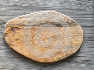 Wooden cutting board of arbitrary shape on the background of gray table surface. Top view. Close-up. Copy space.