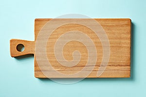 Wooden cutting board on blue background, from above