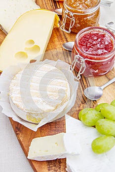 Wooden cutting board with cheese and jams