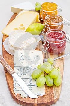 Wooden cutting board with cheese and jams