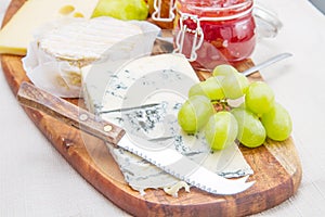 Wooden cutting board with cheese and jams