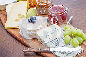 Wooden cutting board with cheese and jams