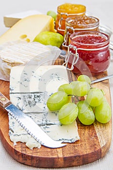 Wooden cutting board with cheese and jams