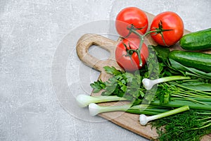 Wooden cutting board with fresh vegetables: cucumbers, tomatoes, parsley, green onion. Healthy organic food, salad ingredients top