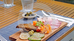 Wooden cutting board with meat and vegetables, cold cuts in restaurant