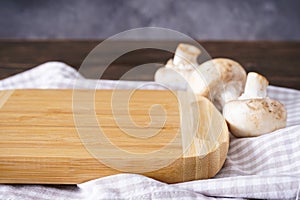 Wooden cutting board and mushrooms on a wooden background