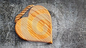 Wooden cutting board in the shape of a heart on a gray background