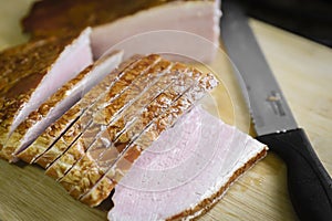 Wooden cutting board with sliced raw picnic ham