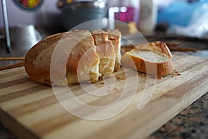 Wooden cutting board with sliced white bread on wooden table