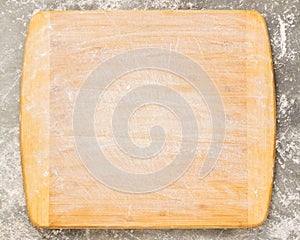 Wooden cutting board sprinkled with empty flour on a gray background. Copy space. Template for text or design. Top view