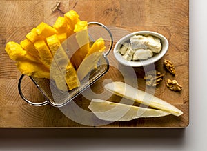 wooden cutting board with sticks of polenta, slice of pear, nuts and cheese