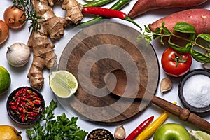 Wooden cutting board, wooden spoon, vegetables and spices