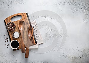 Wooden cutting kitchen board with cooking utensils and spices on light background