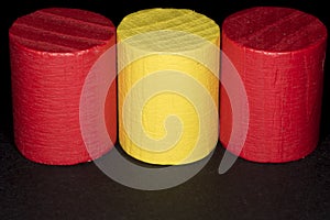 Wooden cylinders painted red and yellow on dark background