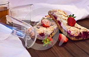 Wooden dark background of planks, white cloth, glasses with tea and homemade pie with cherries and strawberries. Delicious pastrie