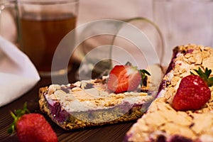 Wooden dark background of planks, white cloth, glasses with tea and homemade pie with cherries and strawberries. Delicious pastrie